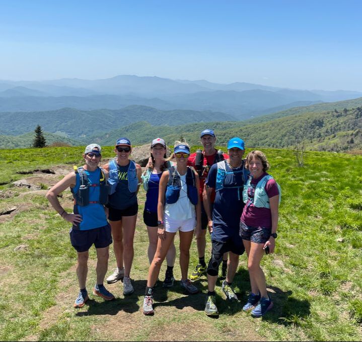 Group of trail runners posing in front of a scenic view over green rolling hills from Adventure Running Co's Appalachian trail running tour